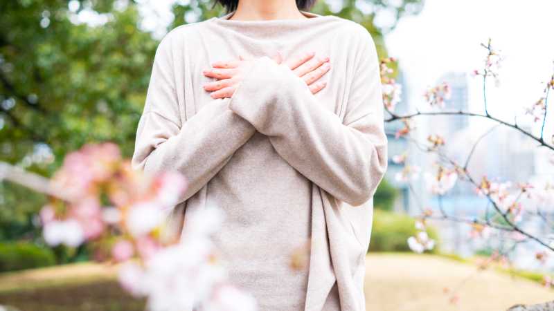 胸で両手をクロスさせて立っている女性